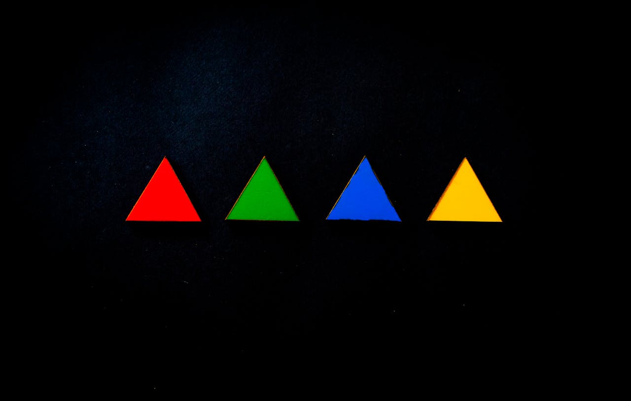 Four colorful triangles arranged on a dark background create a striking abstract composition.