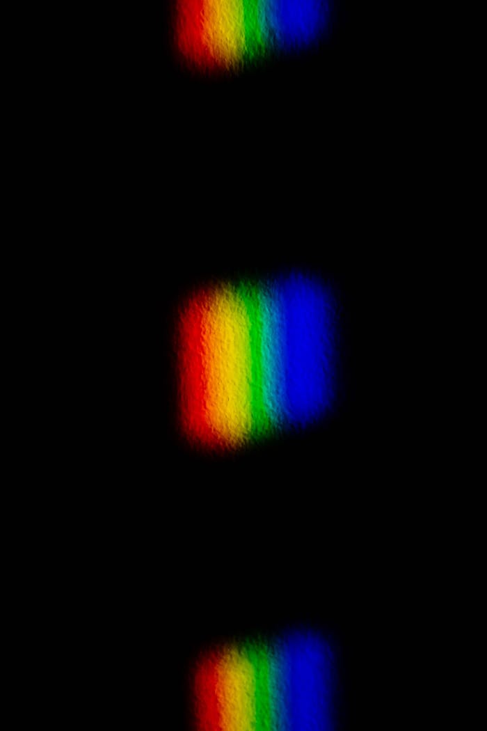 Abstract light spectrum reflection creates a vivid rainbow pattern on a black background.